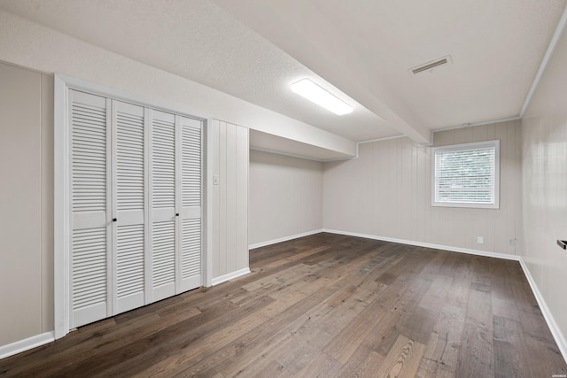 below grade area featuring baseboards, visible vents, and dark wood-style flooring