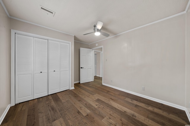 unfurnished bedroom featuring a closet, visible vents, dark wood-style flooring, and ornamental molding