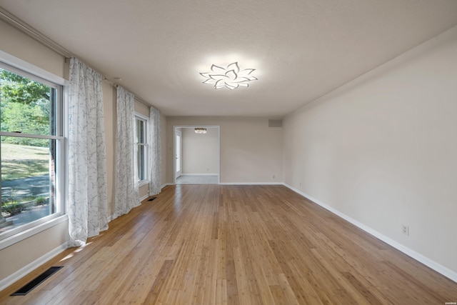 unfurnished room featuring light wood-style floors, baseboards, and visible vents