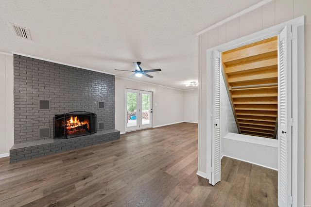 unfurnished living room featuring dark wood-type flooring, a fireplace, visible vents, and crown molding