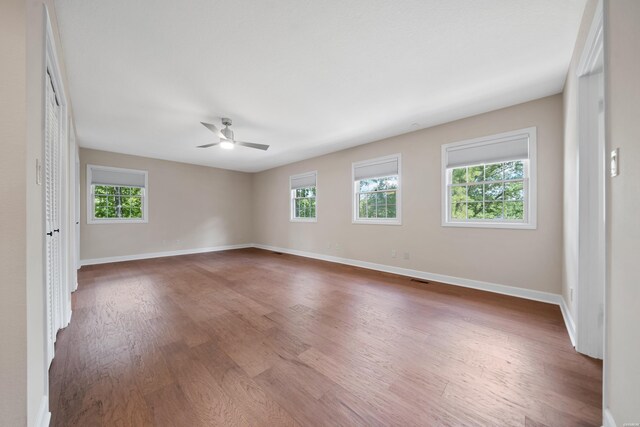 spare room with ceiling fan, dark wood-type flooring, plenty of natural light, and baseboards