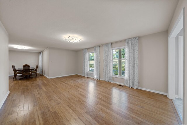 empty room featuring light wood-type flooring, visible vents, and baseboards