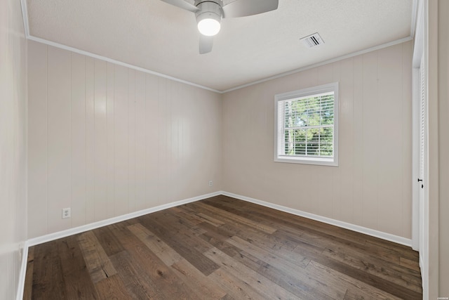 spare room featuring dark wood-style floors, crown molding, visible vents, ceiling fan, and baseboards