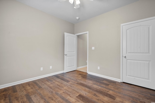 unfurnished bedroom with dark wood-type flooring, baseboards, and a ceiling fan