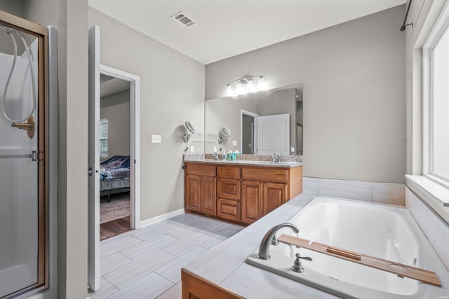 ensuite bathroom with ensuite bathroom, a garden tub, visible vents, double vanity, and a stall shower