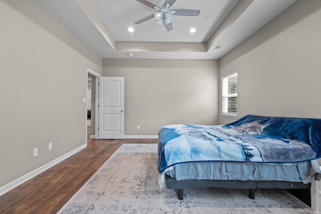 bedroom with recessed lighting, a raised ceiling, visible vents, wood finished floors, and baseboards