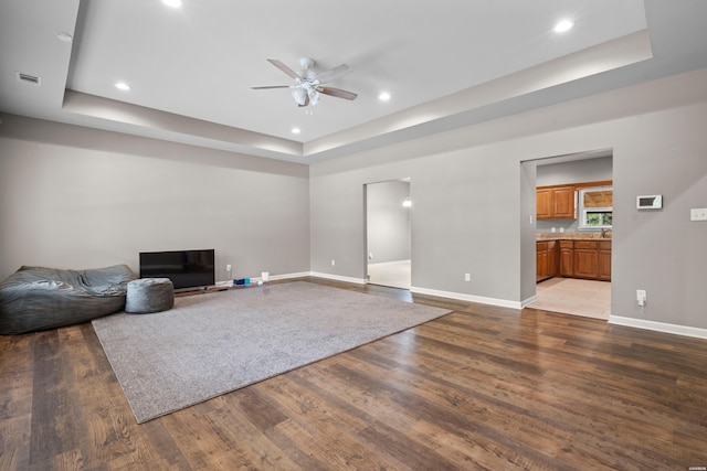 unfurnished living room featuring visible vents, a raised ceiling, and wood finished floors