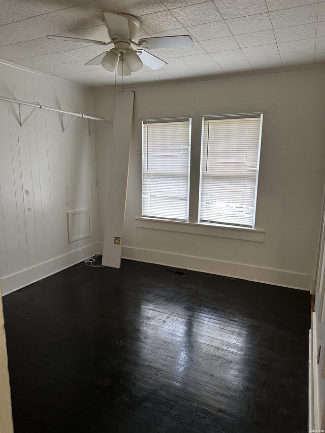 empty room featuring wood finished floors, a ceiling fan, and baseboards