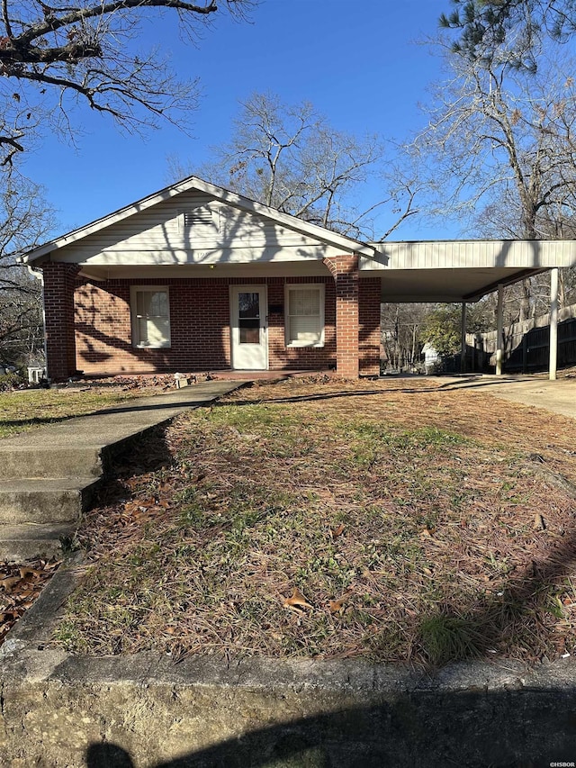 view of front of house featuring driveway, a carport, and brick siding