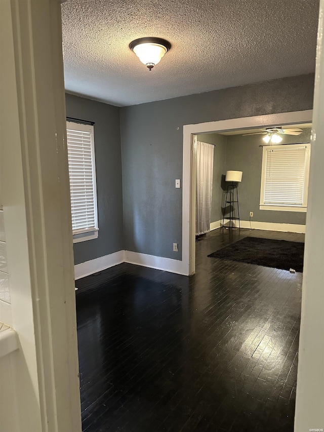 unfurnished room with a textured ceiling, ceiling fan, wood-type flooring, and baseboards