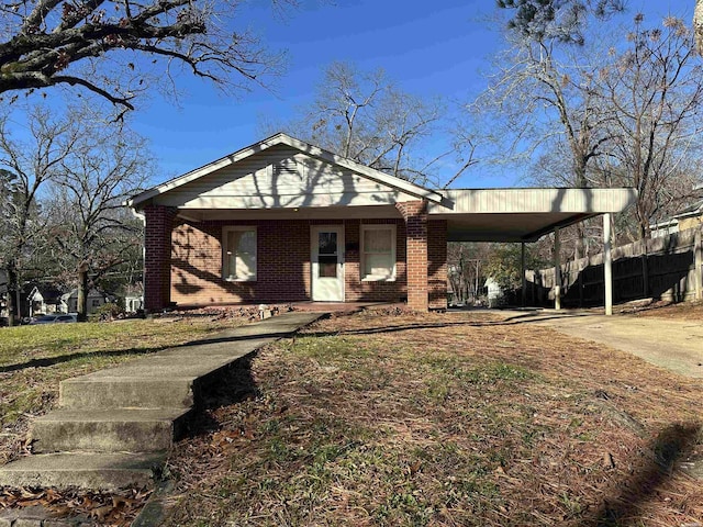 view of front of house with a carport, concrete driveway, brick siding, and fence