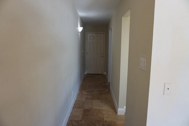 corridor featuring baseboards and stone finish floor