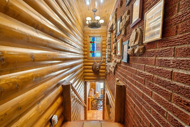 corridor with plenty of natural light, an upstairs landing, log walls, and an inviting chandelier