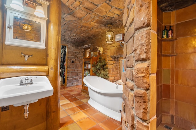 bathroom with a soaking tub, a sink, and tile patterned floors