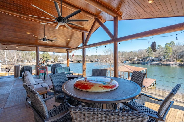 deck with outdoor dining area, a water view, and ceiling fan