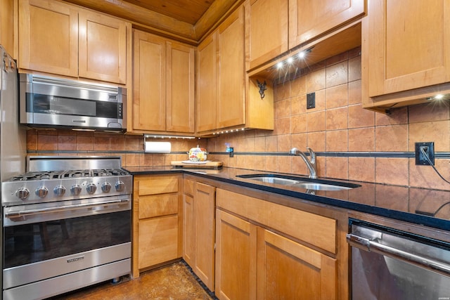 kitchen featuring appliances with stainless steel finishes, dark countertops, a sink, and decorative backsplash