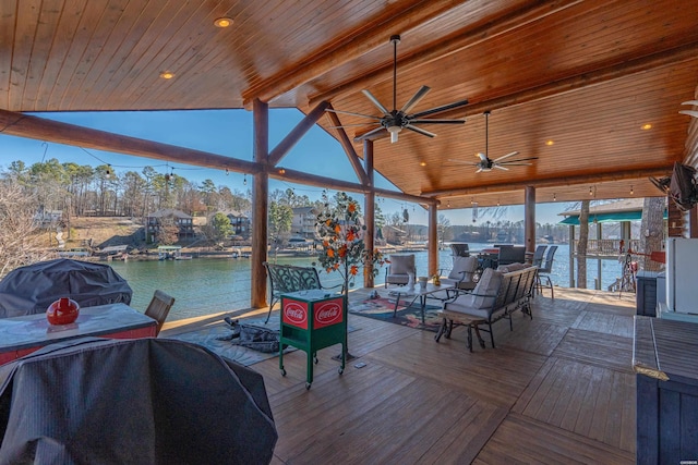wooden terrace featuring a water view, a boat dock, a ceiling fan, and area for grilling