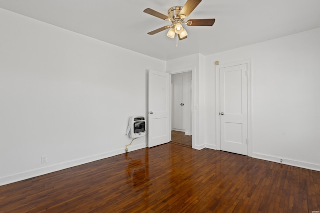 unfurnished bedroom featuring hardwood / wood-style floors, heating unit, a ceiling fan, and baseboards