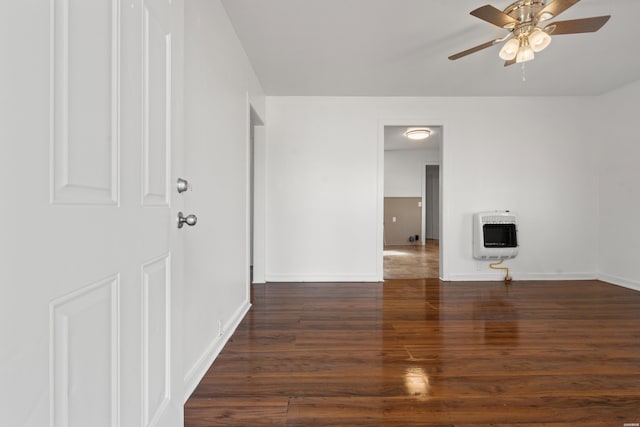 unfurnished living room with heating unit, a ceiling fan, baseboards, and wood finished floors