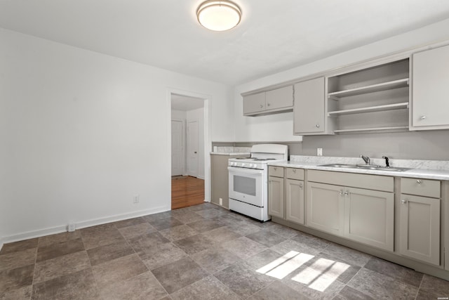 kitchen with baseboards, open shelves, white range with gas stovetop, a sink, and light countertops