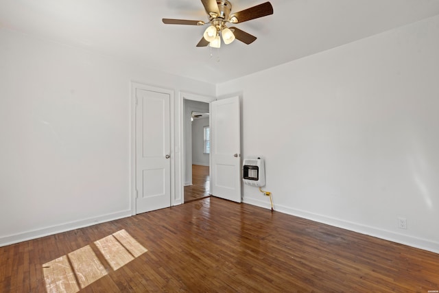 spare room featuring baseboards, heating unit, ceiling fan, and hardwood / wood-style flooring