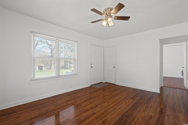 empty room featuring a ceiling fan, baseboards, and dark wood-style flooring