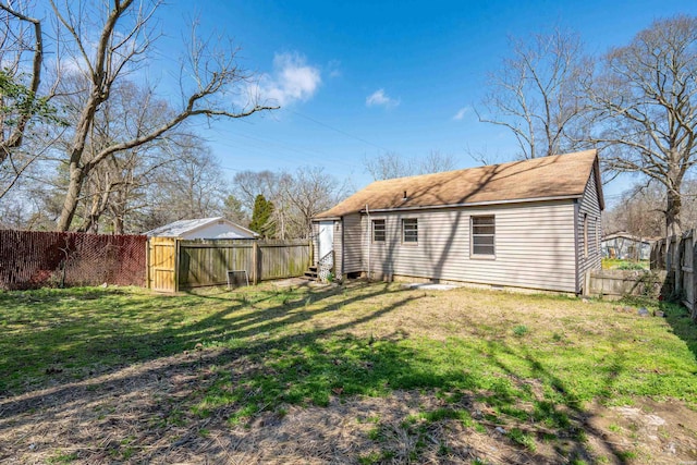 rear view of house featuring entry steps, a lawn, and a fenced backyard