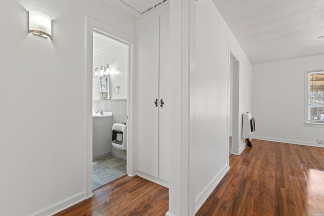 corridor featuring attic access, heating unit, and wood finished floors