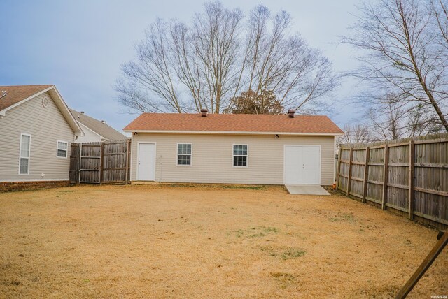 back of house with a fenced backyard and a yard