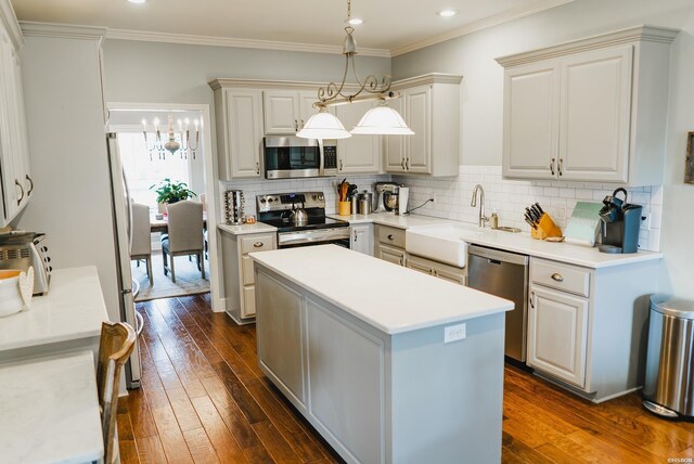 kitchen with stainless steel appliances, light countertops, decorative light fixtures, and a center island