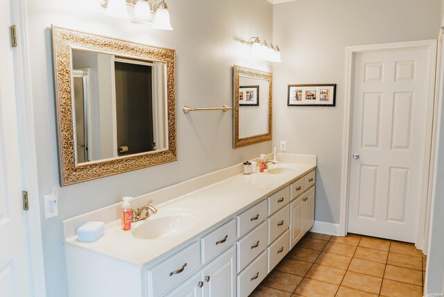 bathroom featuring baseboards, double vanity, a sink, and tile patterned floors