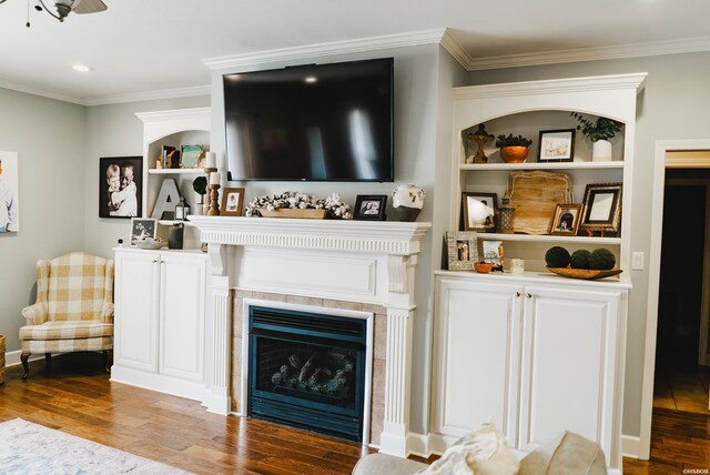 living room with ornamental molding, a ceiling fan, a fireplace, and wood finished floors