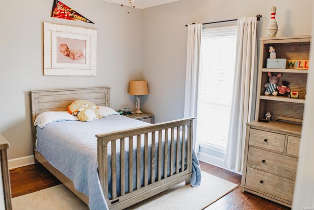 bedroom featuring multiple windows, baseboards, and wood finished floors