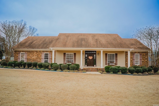 view of front of house featuring a shingled roof, a front lawn, and brick siding