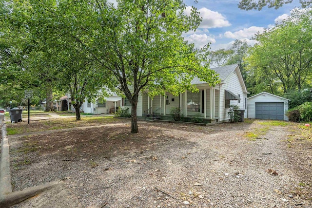 view of front of house with covered porch, a detached garage, an outdoor structure, driveway, and roof with shingles