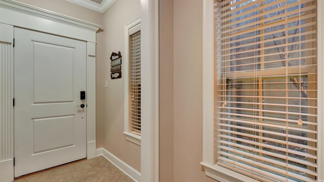 doorway with ornamental molding, light tile patterned flooring, and baseboards