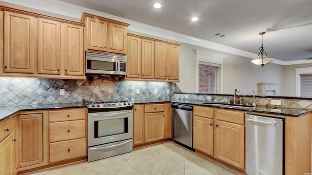 kitchen with dark stone counters, appliances with stainless steel finishes, decorative light fixtures, a sink, and light tile patterned flooring