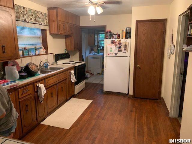 kitchen featuring white appliances, a ceiling fan, dark wood finished floors, washer / dryer, and light countertops