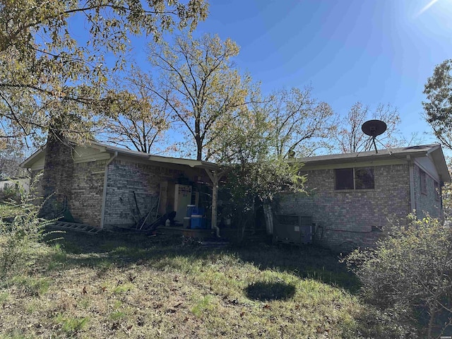 rear view of house with a yard, brick siding, and crawl space