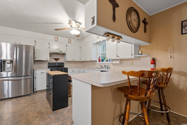 kitchen featuring black gas range, stainless steel fridge with ice dispenser, a peninsula, under cabinet range hood, and white cabinetry