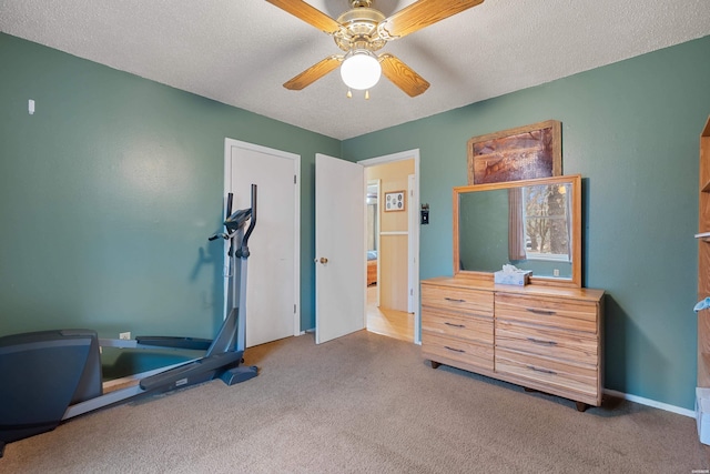 exercise room with carpet, ceiling fan, and a textured ceiling