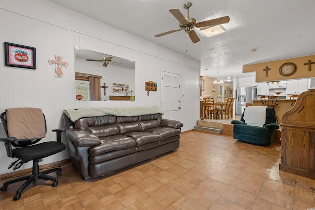 living area featuring ceiling fan and a textured ceiling