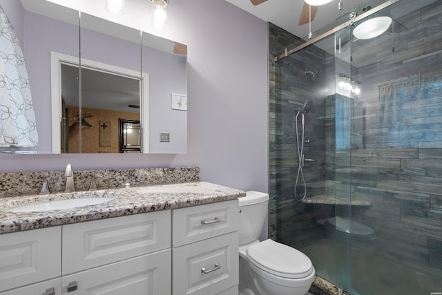 full bath with a stall shower, ceiling fan, vanity, and toilet