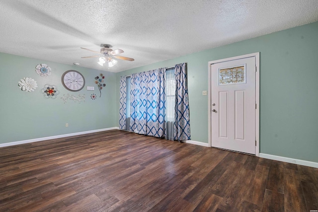 unfurnished room featuring a textured ceiling, dark wood finished floors, a ceiling fan, and baseboards