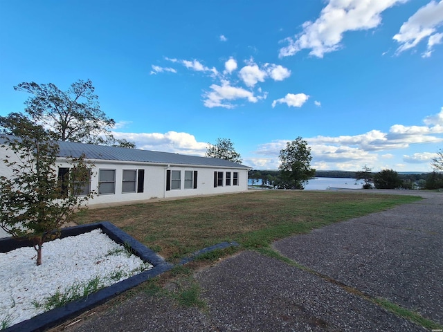 view of front facade with metal roof, a front lawn, a water view, and stucco siding