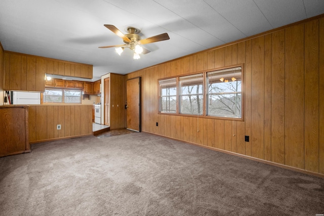 carpeted spare room with wood walls and a ceiling fan