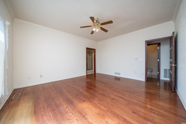 spare room featuring dark wood-style flooring, visible vents, and crown molding