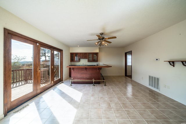 kitchen featuring light tile patterned floors, glass insert cabinets, a kitchen bar, and visible vents