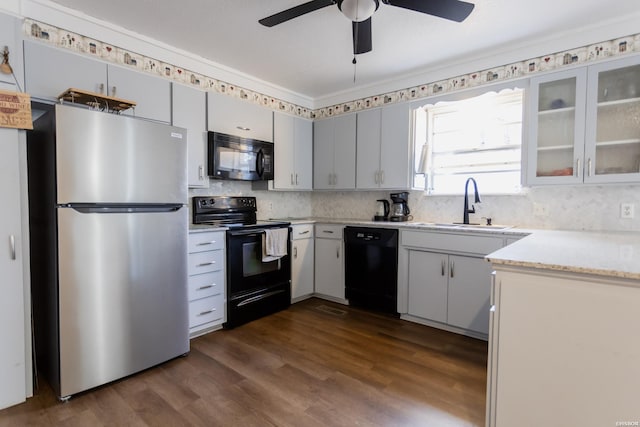 kitchen featuring a sink, light countertops, dark wood-style floors, black appliances, and glass insert cabinets