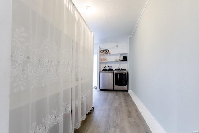 hall with light wood-style floors, baseboards, ornamental molding, and washing machine and clothes dryer